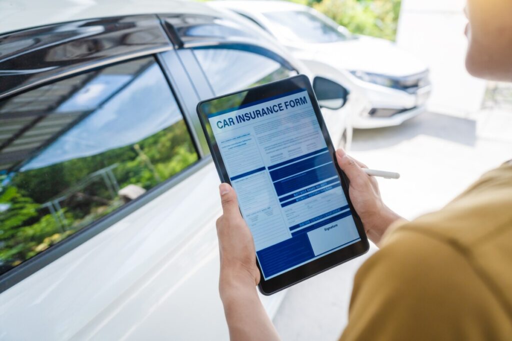 Man fills out a car insurance form after a car accident. Comprehensive motor insurance car damage.